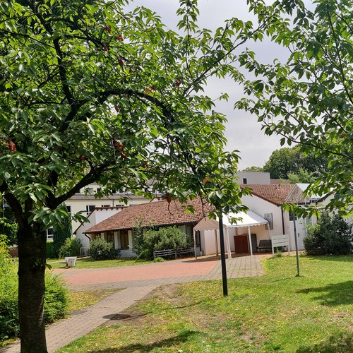 Blick auf die Physiotherapie (Gebäude) im sommerlich grünen Park.